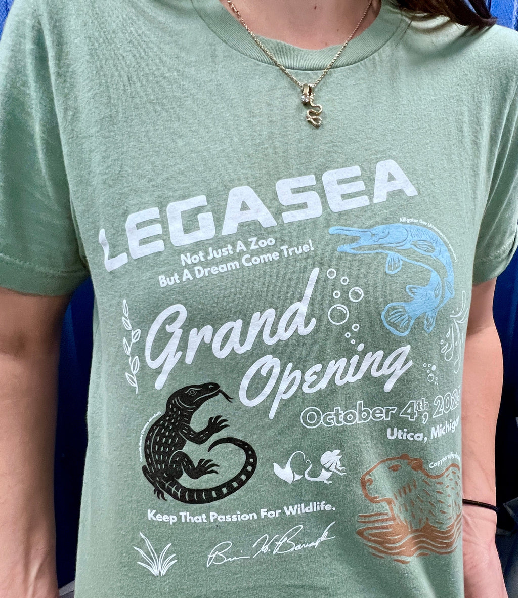 Person wearing a green t-shirt with 'LEGASEA Grand Opening' text and graphics.